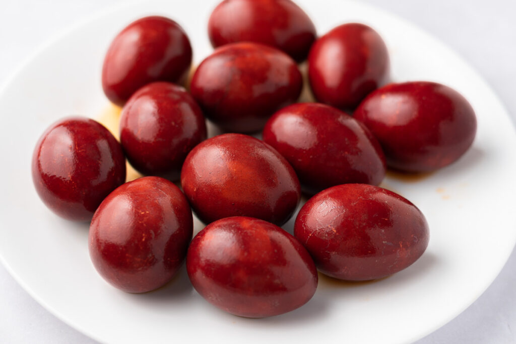 Freshly made red-dyed eggs on a plate.