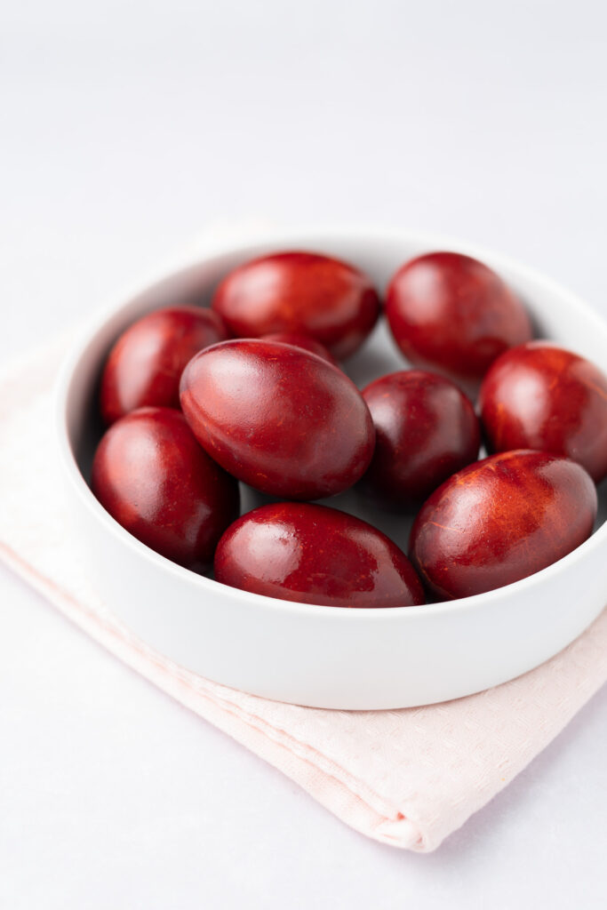 Red-dyed eggs in a white bowl.