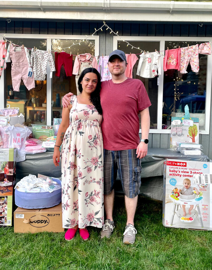 A man and woman at a baby shower standing near gifts.