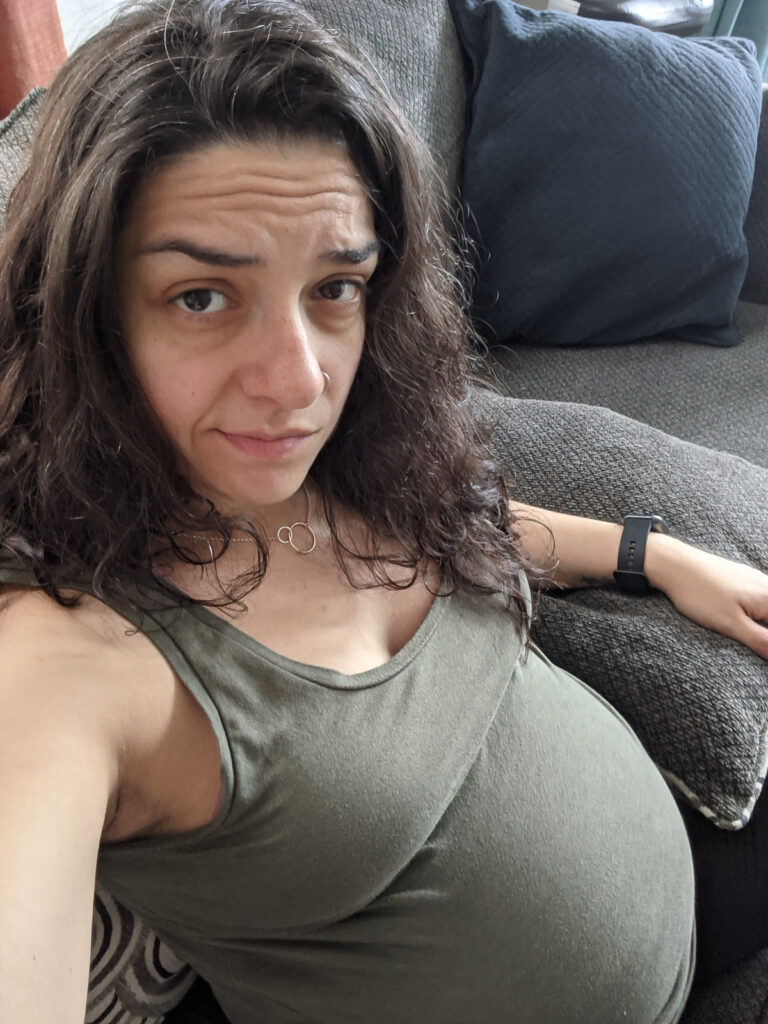 A pregnant woman sitting on a sofa.