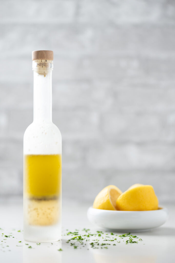 Ladolemono dressing in a bottle and a bowl of cut up lemons.