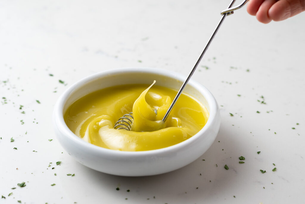 Olive oil and lemon juice being whisked in a small bowl.