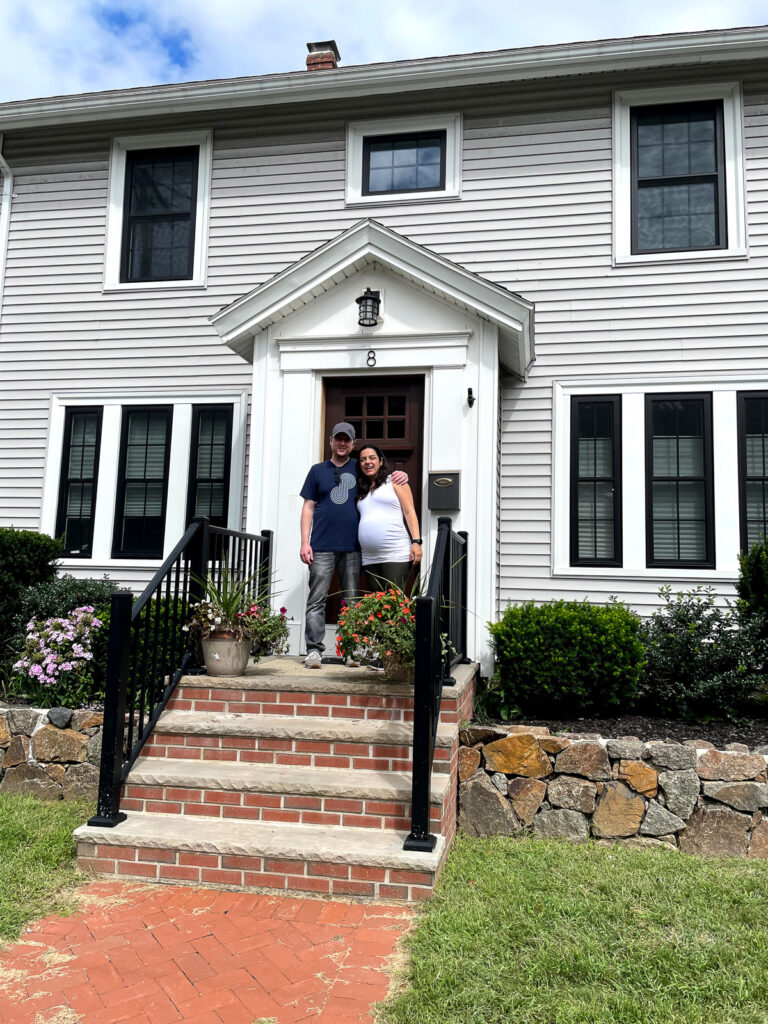 A man and woman standing in front of a house.